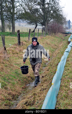 conservationist with bucket, walking along a toad fence, Germany