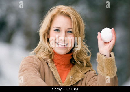 Austria, Salzburger Land, Altenmarkt, Young woman holding a snow ball, smiling, portrait Stock Photo