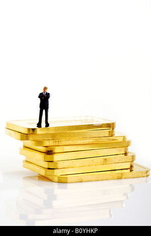 Businessman figurine standing on stack of gold bars Stock Photo