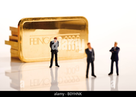 Businessman figurines, in background gold bars Stock Photo