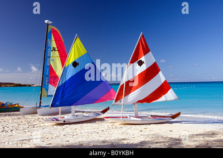 Colorful sailboat sails on the beach with the Holland America cruise ship Westerdam anchored offshore at Half Moon Cay Bahamas Stock Photo