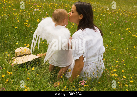 Mother with baby (2-3) in the meadow, angel's wings, rear view Stock Photo