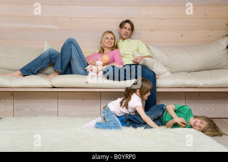 Boy (8-9) and girl (6-7) fighting on carpet, parents in background, portrait Stock Photo