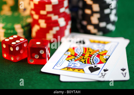 Stacks of gambling chips playing cards and dice on green background Stock Photo