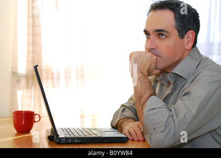 Man sitting at a desk and looking into his computer Stock Photo