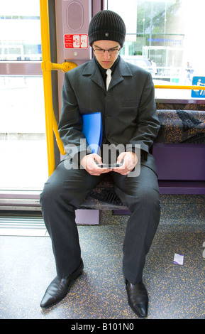 young man using portable gamer seated on public transport Stock Photo