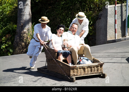 dh wicker basket toboggan MONTE FUNCHAL MADEIRA PORTUGAL Tourist couple on ride holiday tourists sledge Stock Photo