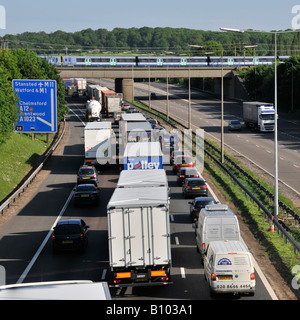 Transport choice M25 motorway nose to tail slow moving traffic watching fast passenger train on railway bridge junction 28 Brentwood Essex England UK Stock Photo