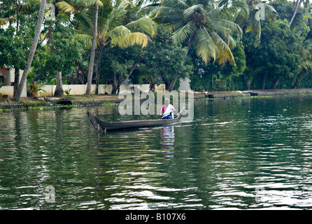 INDIA KERALA Elderly Indian woman rowing her wooden canoe down the canals in the backwaters of Kerala Stock Photo