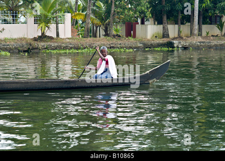 INDIA KERALA Elderly Indian woman rowing her wooden canoe down the canals in the backwaters of Kerala Stock Photo