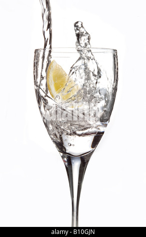 Water being poured into a glass with a slice of lemon Stock Photo