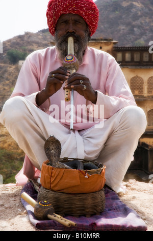 Snake Charmer playing flute for dancing Cobra in basket perform outside Amber Palace, Rajasthan, India Stock Photo