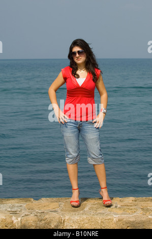 Full length portrait of a fashionable Arabic woman standing by the sea Stock Photo