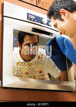 A young man staring into the oven, in the kitchen Stock Photo