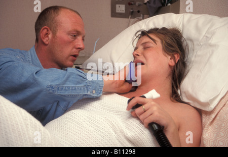 young woman in labour in hospital partner sponging down her face Stock Photo