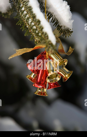 JINGLE BELLS CHRISTMAS ORNAMENT HANGING OUTSIDE ON TREE IN SNOW Stock Photo