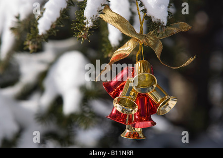 JINGLE BELLS CHRISTMAS ORNAMENT HANGING OUTSIDE ON TREE IN SNOW Stock Photo