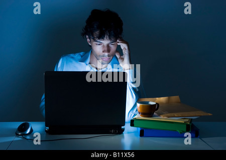 Young businessman on his laptop with headache for the excessive work and the late hours Stock Photo