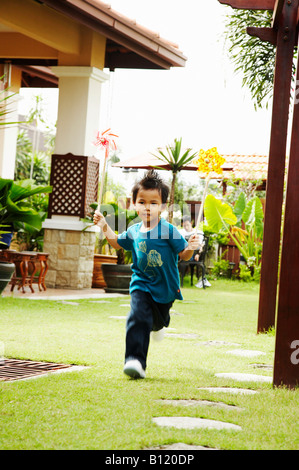 Siblings playing in backyard and running through sprinkler in summer ...