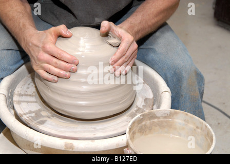 Potter centering clay on potter's wheel starting to form a pot Stock Photo