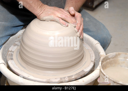 Potter centering clay on potter's wheel starting to form a pot Stock Photo