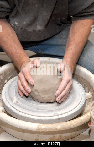 Potter centering clay on potter's wheel starting to form a pot Stock Photo