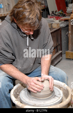 Potter centering clay on potter's wheel starting to form a pot Stock Photo