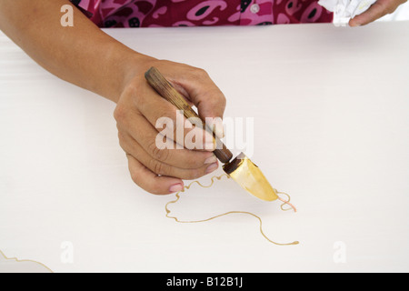 Batik painting closeup hand holding canting Stock Photo