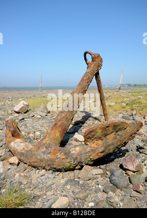 An old rusty anchor on a stone beach Stock Photo