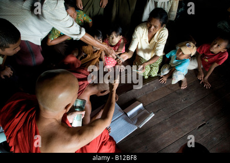 Buddhist monk giving money to cyclone affected people in a monastery in Kyauktan township of Yangon Myanmar, Burma 15 May 2008 Stock Photo