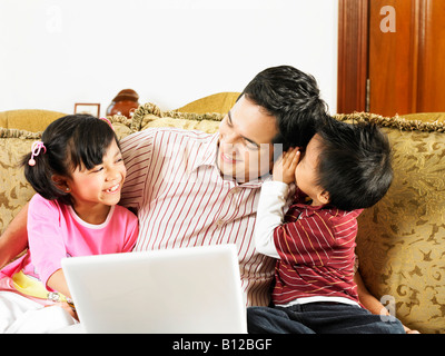 Son whisper to father, watched by daughter Stock Photo