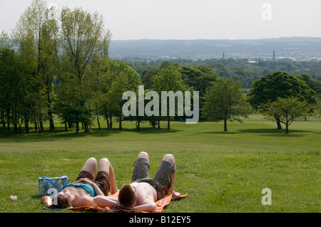 young couple lying on grass sunbathing in Haigh Hall country park Wigan Lancashire summer afternoon Stock Photo