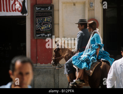 Senorita wearing flamboyant festival dress is riden to the bullfight on horseback in the Aldalucian town of Rhonda Stock Photo