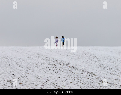 Two children on a snowy hillside, Essex, UK Stock Photo