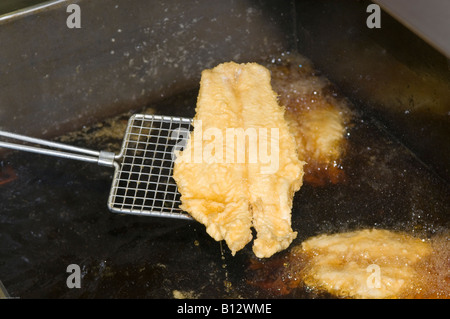 Single fish draining over deep fat fryer Stock Photo