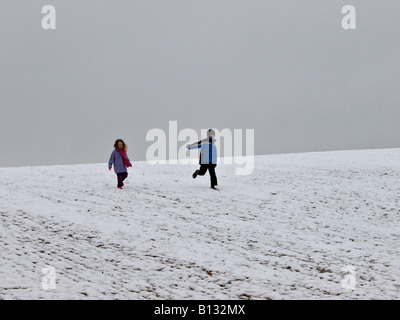 Two children running down a snowy hill Stock Photo