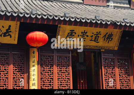 Lattice work elaborately tiled roof red lantern and inscribed motto above entrance to the jade Buddha pavillion Shanghai China Stock Photo