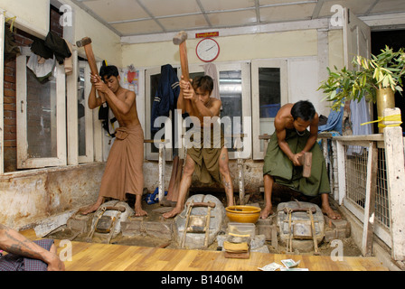 gold beating young men beating with 3 kg beater beating hours on little in leather packed gold pieces MANDALAY BURMA Stock Photo