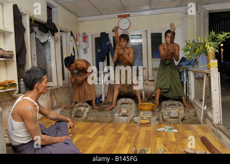 gold beating young men beating with 3 kg beater beating hours on little in leather packed gold pieces MANDALAY BURMA Stock Photo