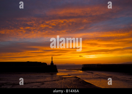 Sunset behind the lighthouse and harbour wall of Maryport, Cumbria, England UK Stock Photo