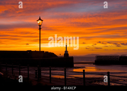 Sunset behind the lighthouse and harbour wall of Maryport, Cumbria, England UK Stock Photo