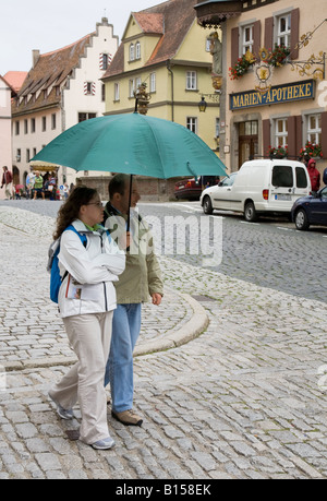 People on holiday using umbrella in rain Rothenburg Germany Stock Photo