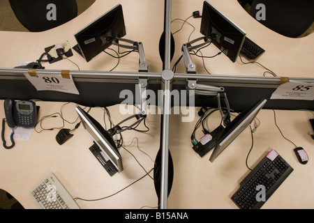 Four connected office desks, with swinging monitor arms, keyboards, mice and telephones. Stock Photo