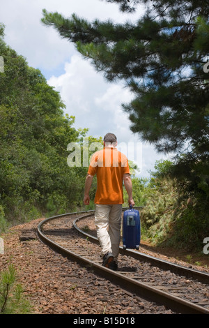 Man walking on a railroad with his suitcase Stock Photo