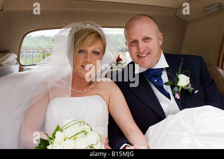 A bride and groom take their first ride as a newly married couple after their wedding in the Bridal car. Stock Photo