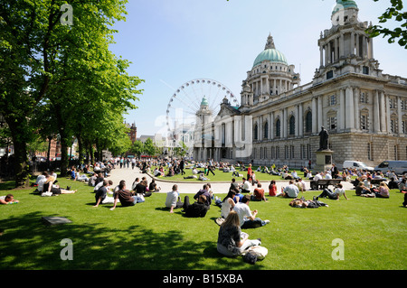 Belfast City hall with crowd sitting relaxing in the May sunshine Stock Photo