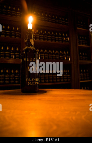 dh Adegas de Sao Francisco FUNCHAL MADEIRA Bottle with candle in Madeira wine lodge with racked bottles blandy Stock Photo