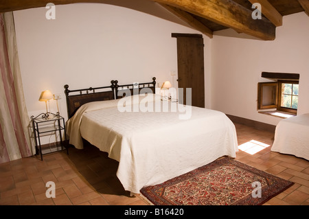 Double bed in a rustic hotel room with wooden beams in the ceiling Countryside of Bologna Emilia Romagna Italy Stock Photo