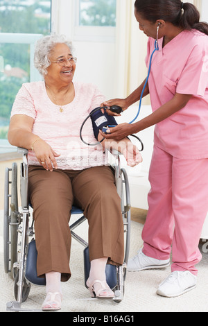 Nurse taking senior woman’s blood pressure Stock Photo