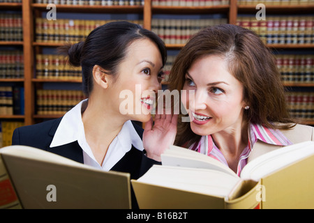 Multi-ethnic women whispering in law library Stock Photo
